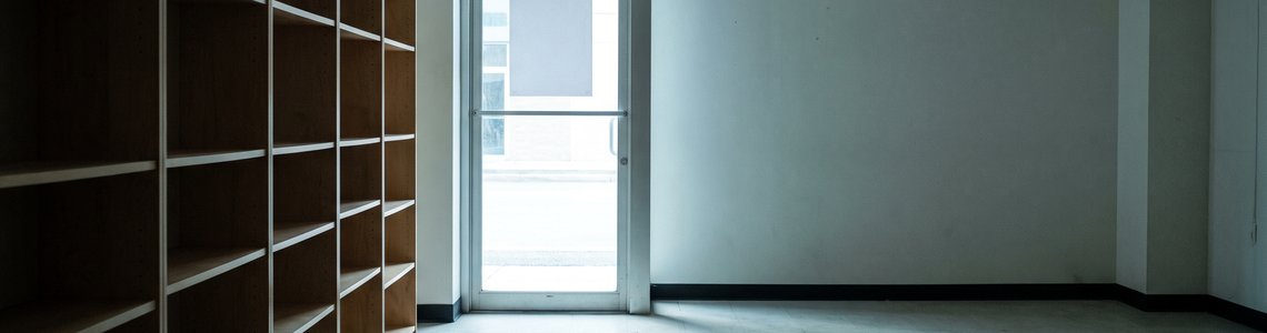 Leergeräumtes Ladengeschäft mit leeren Regalen und geschlossener Glastür