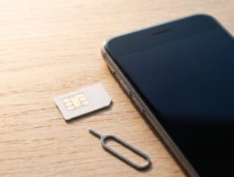 SIM-Karte neben Smartphone und Auswurfwerkzeug