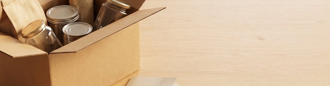 Offener Versandkarton mit unbedruckten Glaesern und Dosen auf Holz