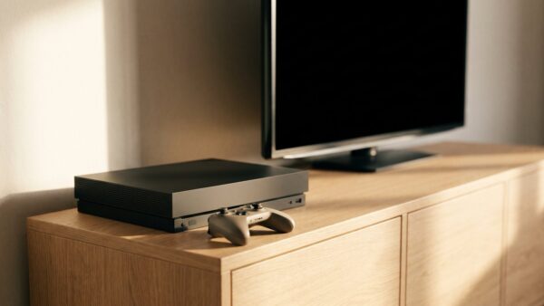 spiele verkaufen ankauf bild 2 Schlichte Spielkonsole mit Controller vor einem dunklen Fernseher