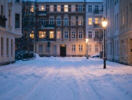 streupflicht winterdienst bild 1 Verschneite Wohnstraße im Morgengrauen mit ungeräumten Gehwegen und Laternenlicht