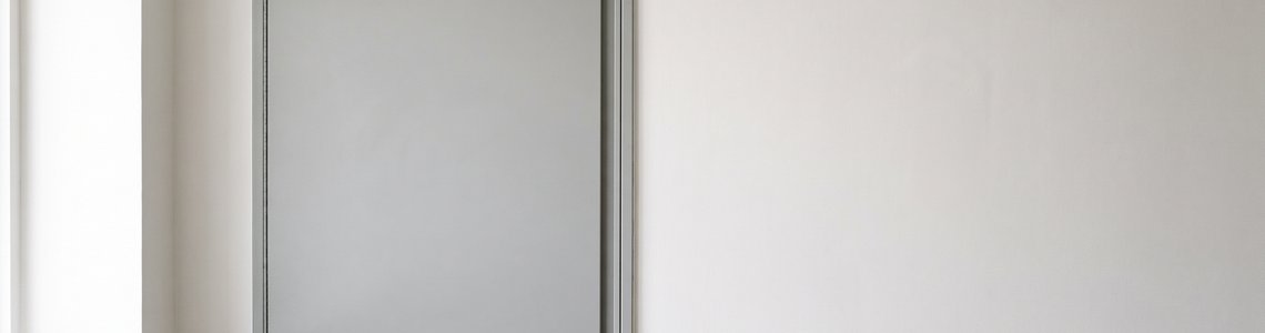 Geschlossener grauer Zählerschrank an einer hellen Wand in einem ruhigen Treppenhaus