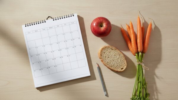 Leerer Papierkalender neben Apfel, Brotscheibe und Karotten als Symbol für die Aktionstage gegen Lebensmittelverschwendung