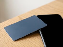 tchibo card bild 1 Unbedruckte blaue Kundenkarte neben Smartphone mit schwarzem Bildschirm