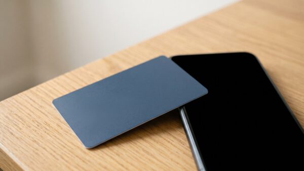 tchibo card bild 1 Unbedruckte blaue Kundenkarte neben Smartphone mit schwarzem Bildschirm