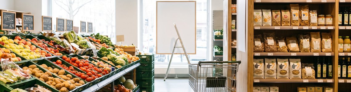 Supermarktgang mit Einkaufswagen und einem leeren Schild, das gerade ausgetauscht wird