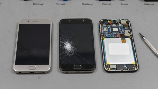 telekom rueckgabedeal bild 3 Drei Smartphones mit Kratzern, gesprungenem Display und geöffnetem Gehäuse auf einer Werkbank