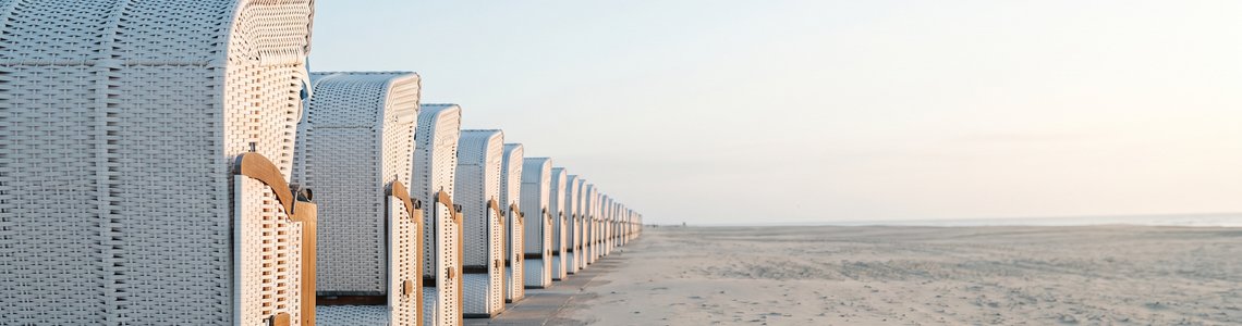 Leere Strandpromenade mit geschlossenen Strandkörben im Morgenlicht