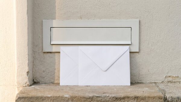 Weißer Briefkastenschlitz mit zwei unbeschrifteten Umschlägen davor