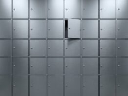 Wand aus gleich großen unbeschrifteten Metalltüren, eine davon einen Spalt geöffnet