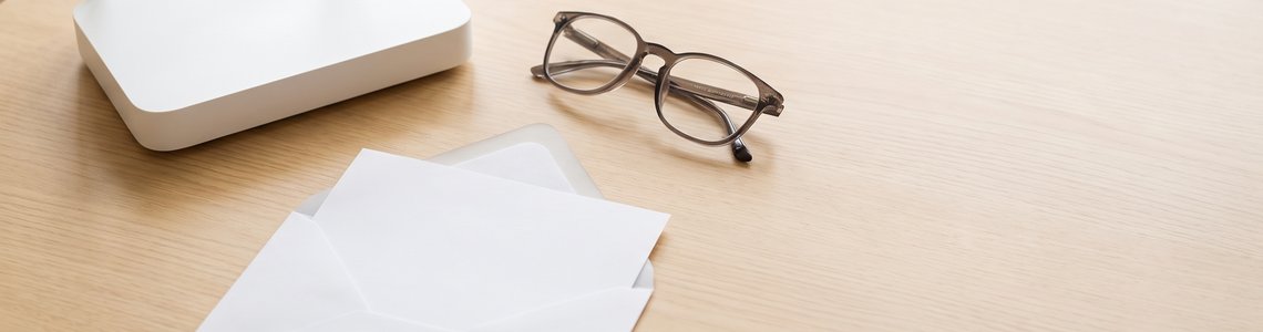 Weißer Router, geöffneter Briefumschlag und Lesebrille auf hellem Holztisch