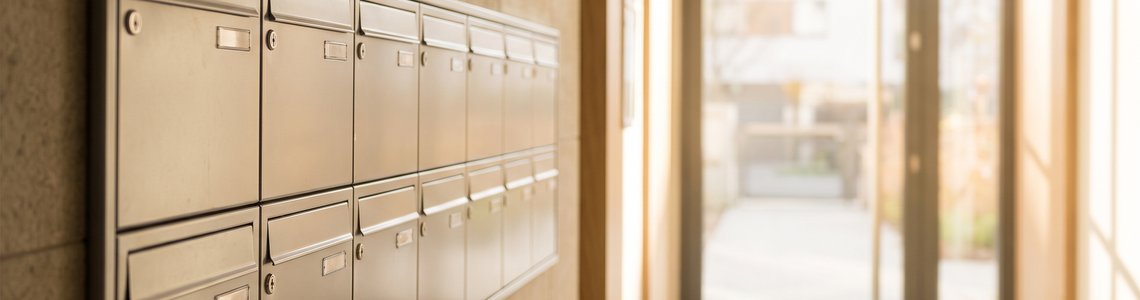 Heller Hauseingang eines Mehrfamilienhauses mit unbeschrifteten Briefkästen im Tageslicht