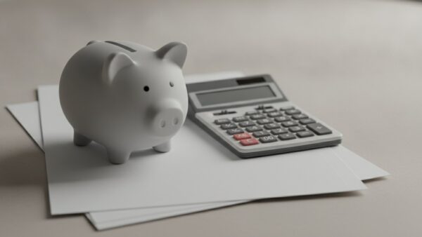 wehrdienst rente bild 2 Graues Porzellan-Sparschwein auf einem Papierstapel neben einem Taschenrechner mit leerem Display