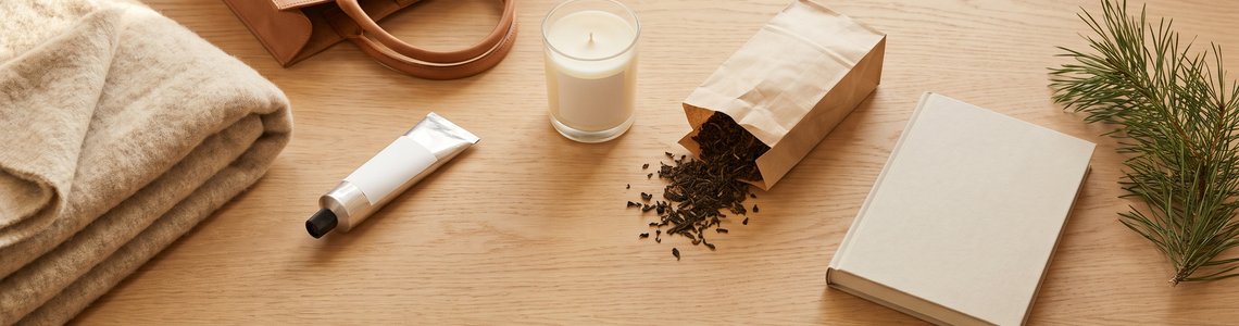 Wolldecke, Tasche, Handcreme und Kerze als Weihnachtsgeschenke auf hellem Holz