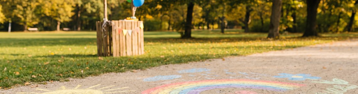 Bunte Kreidezeichnungen auf einem Parkweg mit Luftballons im herbstlichen Hintergrund