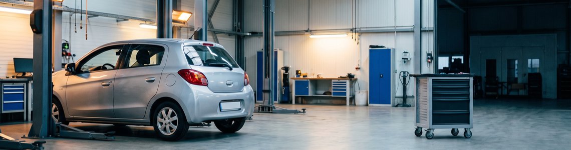 Silbernes Auto auf einer Hebebühne in einer aufgeräumten Kfz-Werkstatt