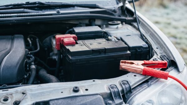 wintercheck auto bild 1 Starterbatterie im geöffneten Motorraum mit einer roten Starthilfeklemme daneben