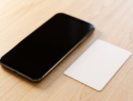 Smartphone mit dunklem Bildschirm neben einem leeren weißen Kärtchen