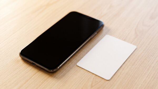 wlan qr code bild 1 Smartphone mit dunklem Bildschirm neben einem leeren weißen Kärtchen