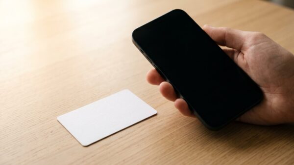 wlan qr code bild 2 Hand hält ein Smartphone über ein leeres weißes Kärtchen