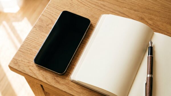 wlan speedtest bild 2 Smartphone mit dunklem Bildschirm neben leerem Notizbuch und Stift
