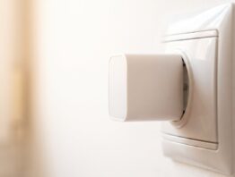 Nahaufnahme eines weißen Steckdosenadapters in einer Wandsteckdose