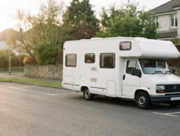 Reisemobil parkt am rechten Fahrbahnrand einer leeren Vorstadtstraße