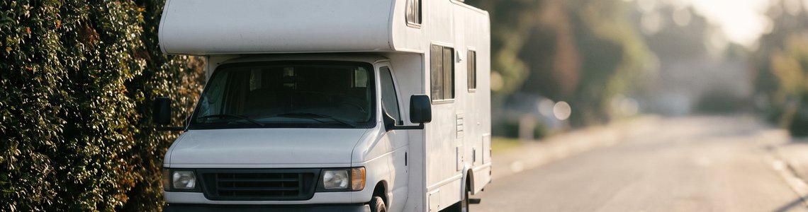 Weißes Reisemobil parkt am Rand einer ruhigen Wohnstraße im Morgenlicht