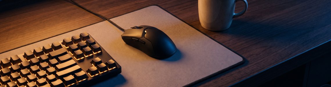 Beleuchtete Gaming-Tastatur und Maus auf einem dunklen Schreibtisch im abgedunkelten Zimmer