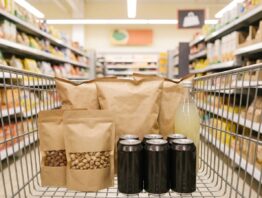 Einkaufswagen mit Chipstüten, Nüssen und Getränkedosen in einem Discounter