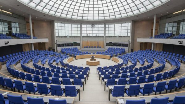 Leerer Plenarsaal mit Sitzreihen im Halbrund unter einer Glaskuppel
