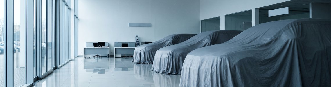 Autohaus-Showroom mit abgedeckten Neuwagen