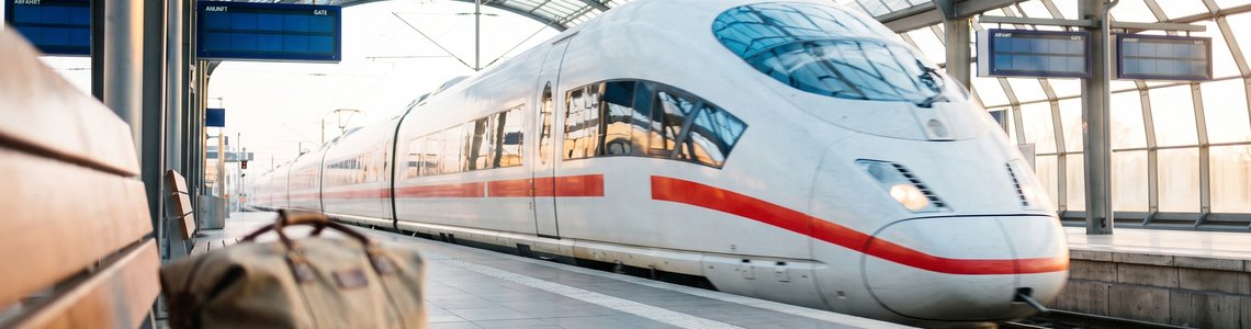 Weißer Hochgeschwindigkeitszug fährt in einen hellen, überdachten Bahnhof ein