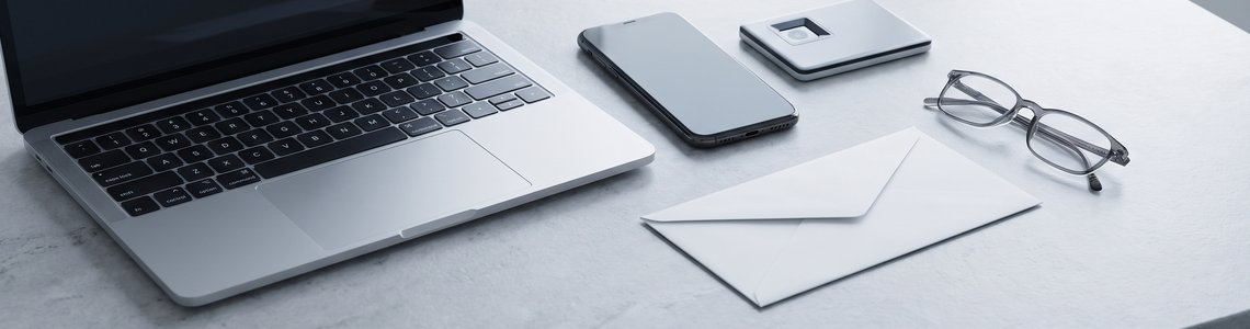 Steintisch mit Laptop, Smartphone, kleinem Lesegerät und Briefumschlag für den Login ins Online-Banking