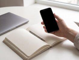congstar login bild 1 Hand mit Smartphone neben einem zugeklappten Laptop als Sinnbild für den Wechsel vom Browser zur App
