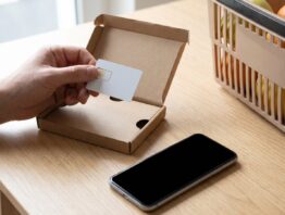 SIM-Karte aus einem Prepaid-Starterset über einem Smartphone und Einkaufskorb