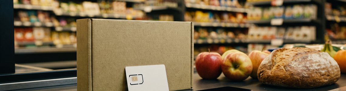 Prepaid-Starterset mit SIM-Karte und Smartphone auf dem Kassenband im Supermarkt