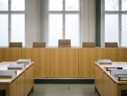 Leerer Sitzungssaal eines Gerichts mit Richtertisch und geschlossenen Aktenordnern