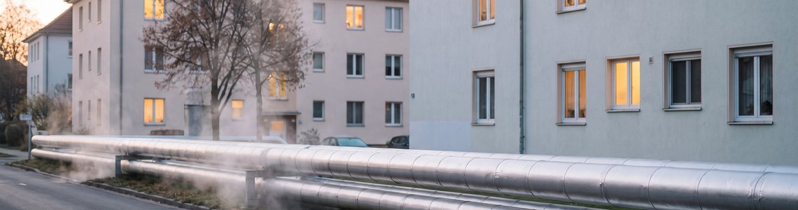 Wohnsiedlung im Herbst mit oberirdisch verlegten Fernwärmerohren im Vordergrund