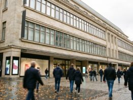 Kaufhausfassade in einer Fußgängerzone mit Passanten im Herbst