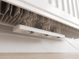 Weiße Lüfterleiste mit drei kleinen Ventilatoren magnetisch unter einem Plattenheizkörper befestigt