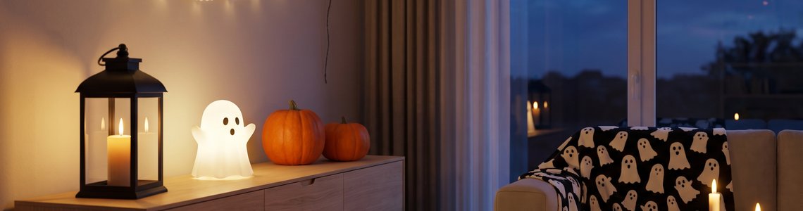 Skandinavisches Wohnzimmer am Abend mit schwarzer Laterne, Geister-Leuchte, Kürbissen und einer Geister-Lichterkette
