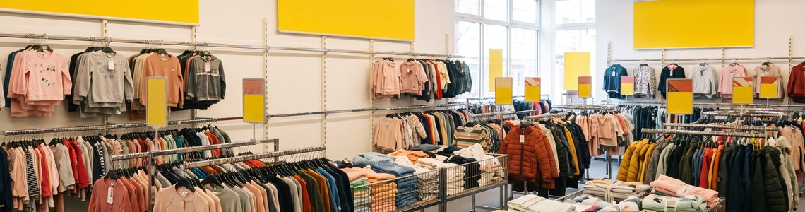 Halb leere Kleiderständer und Wühltische in einem kleinen Textil-Discounter