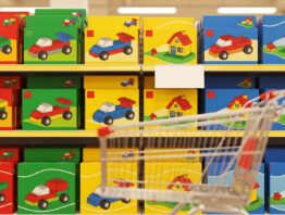 Aktionsregal mit bunten Spielzeugkartons und Einkaufswagen in einem Discounter