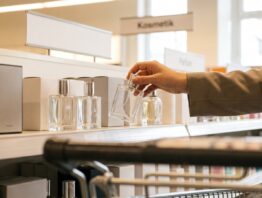 lidl parfum bild 1 Hand greift im Drogerieregal eines Supermarkts nach einem schlichten Parfumflakon