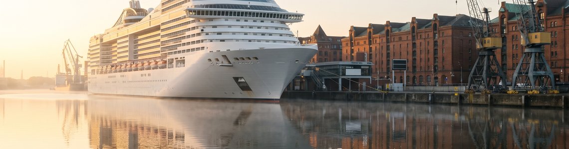 Großes Kreuzfahrtschiff im Morgenlicht an einem Terminal in einer norddeutschen Hafenstadt