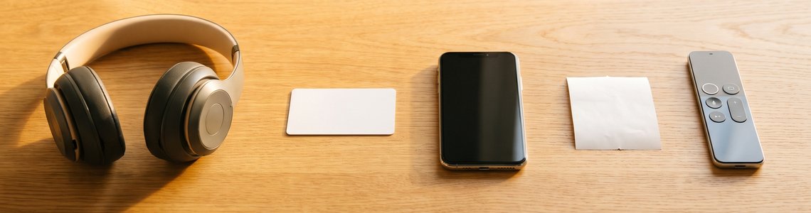 Kopfhörer, Kundenkarte, Smartphone und Fernbedienung auf einem Holzschreibtisch