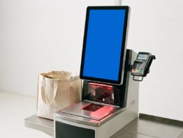 Selbstbedienungskasse mit Touchscreen, Scanner und Ablage mit gefüllter Einkaufstasche