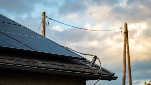 Solarmodule auf einem Hausdach mit Anschlusskabel und Stromleitung im Hintergrund