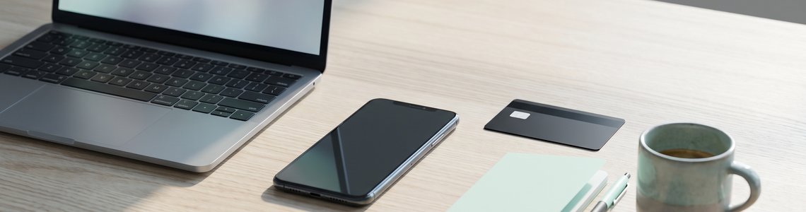 Schreibtisch mit Laptop, ausgeschaltetem Smartphone und schwarzer Karte ohne Aufdruck für den Login beim Online-Broker